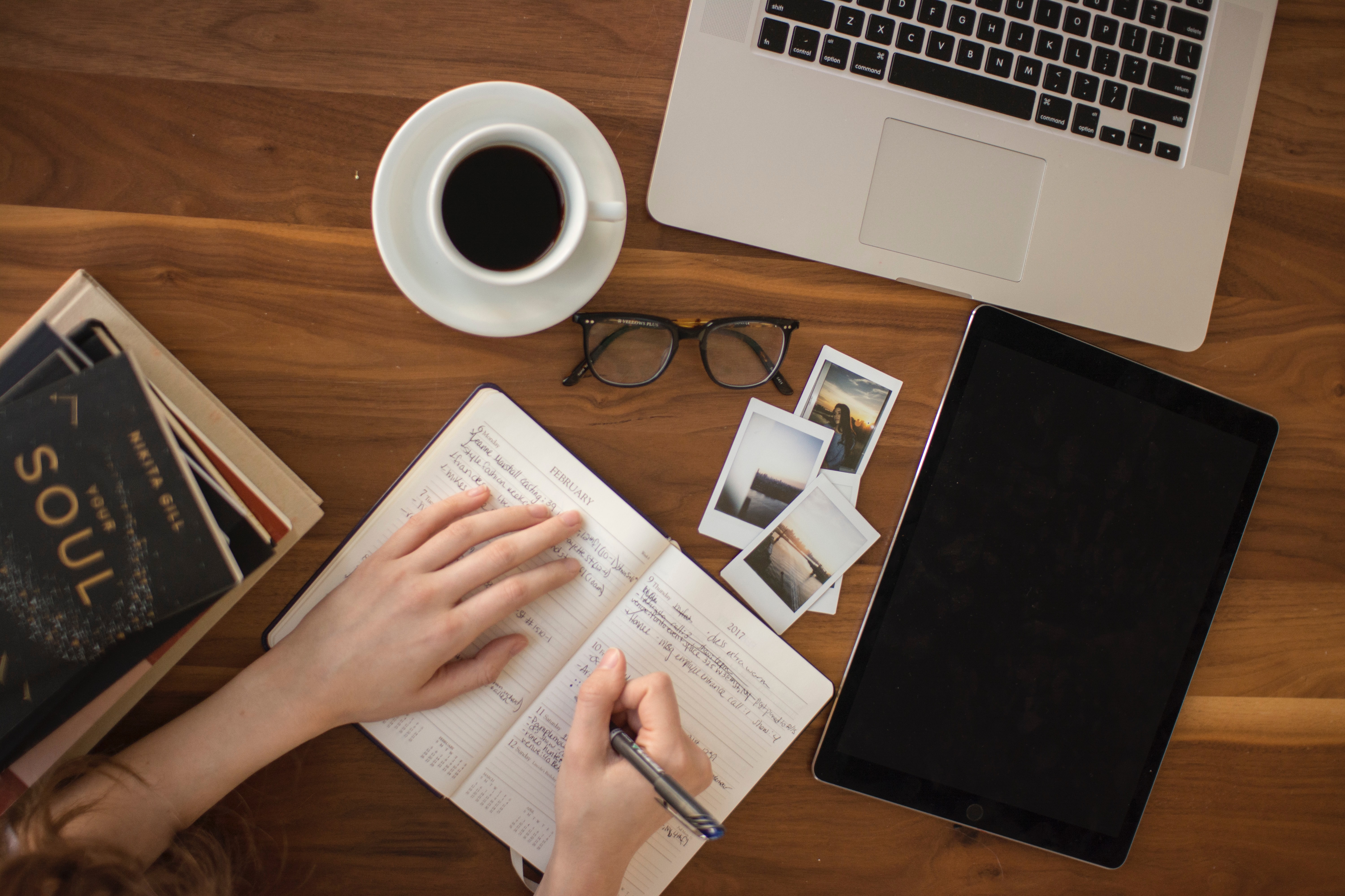 Wood Desk writing in notebook with coffe cup laptop books